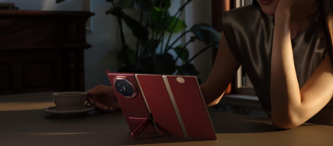 Huawei Mate XT Ultimate tri-fold smartphone propped open, representing the evolution of foldable phones beyond the original book-style form.