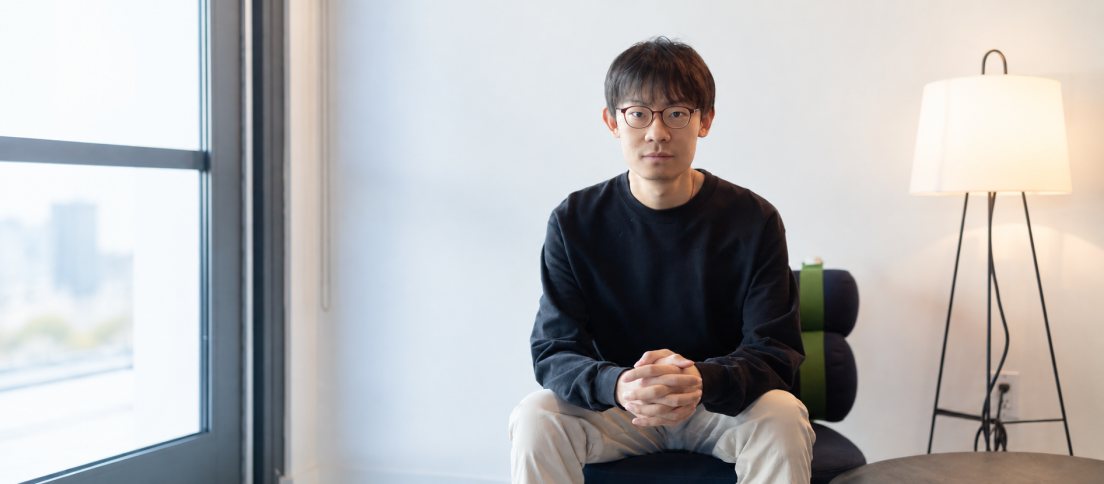 Zhengyang Yang seated by a large window in a calm interior for his DesignWhine interview on the end-to-end AI product designer.