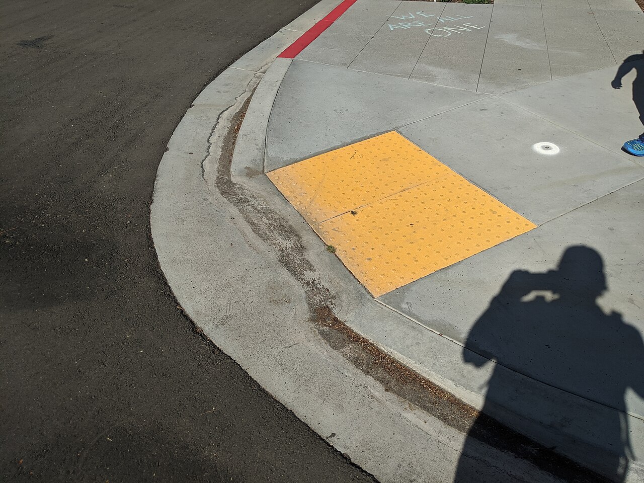 The 15-Minute City Has an Imaginary Resident A lowered curb crossing with tactile paving in San Diego.