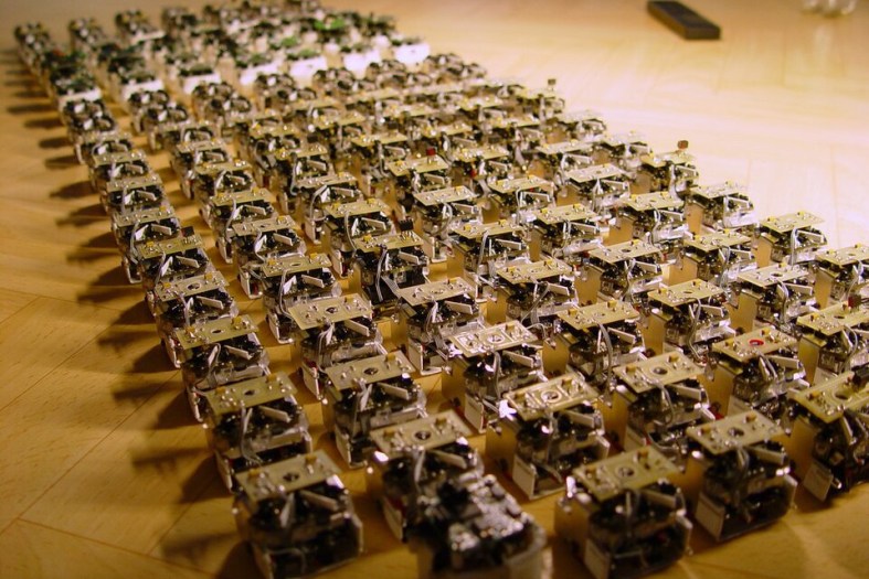 AI Agents Are Starting to Treat the Open Web Like a Sandbox A large swarm of small open-source robots arranged in rows, used by Wikimedia to illustrate the scale and coordination of automated agents.